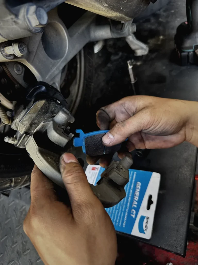 Technician fitting new brake pads on a scooter at MotoNorte